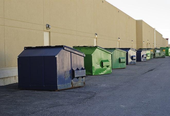 a row of yellow and blue dumpsters at a construction site in Gonzalez